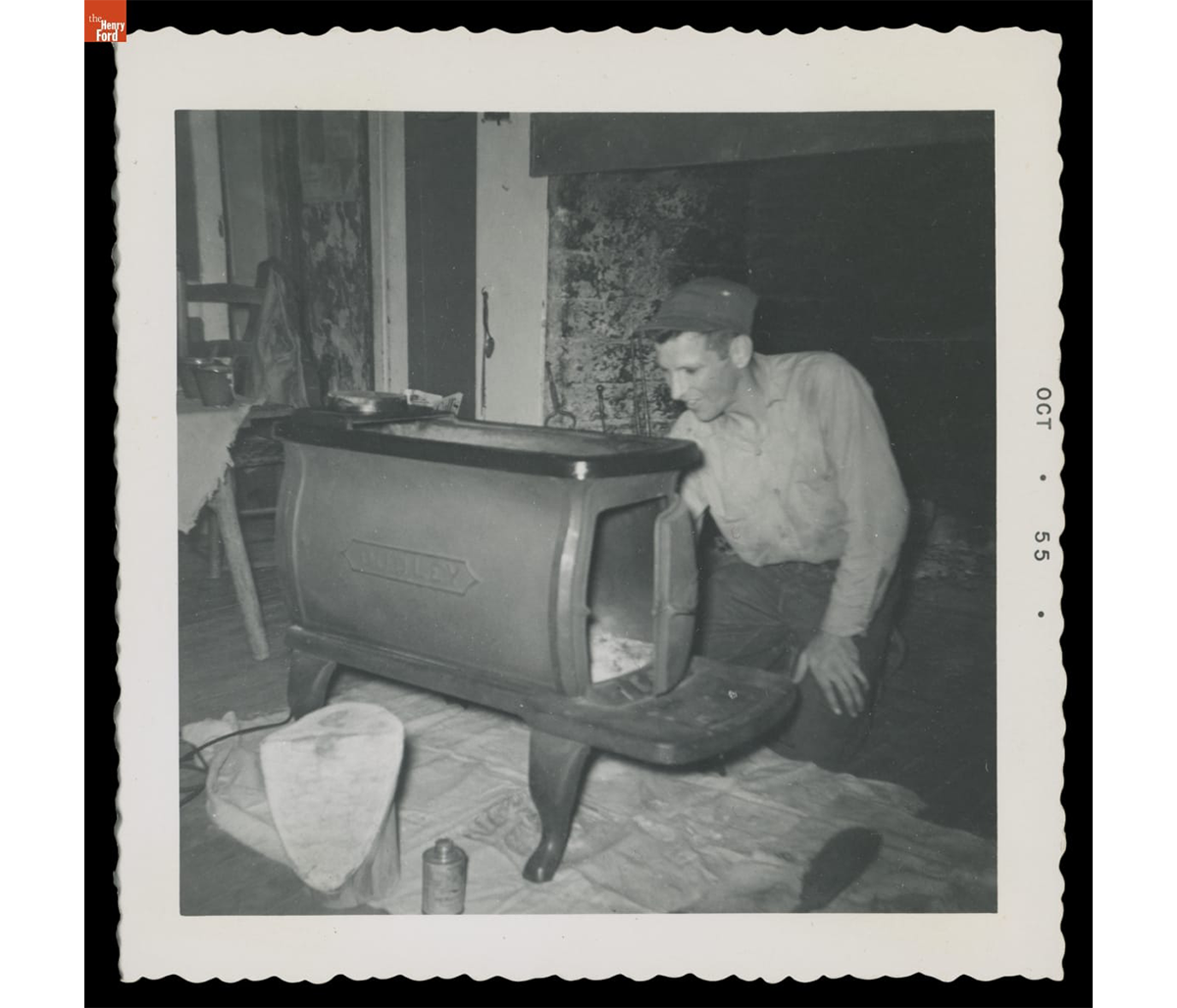 Bob Kelley maintaining the heating stove, Dudley, in the Kelley farmhouse, Andover, Connecticut, 1955. THF723675.