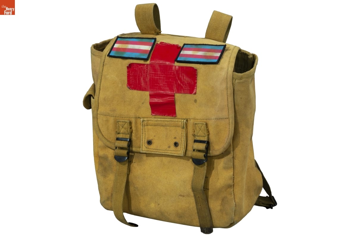 Medic Bag, Used During Protests in Detroit in 2020 Khaki-colored knapsack or backpack with cross made out of red duct tape and striped patches at top